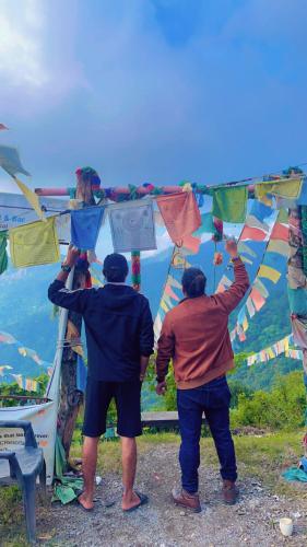 two men standing on top of a hill with kites at TEC Resort and bar in Dharān Bāzār