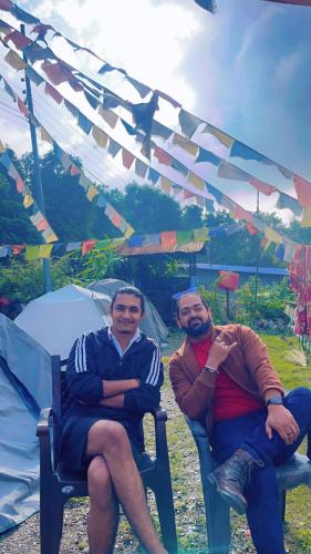 two men sitting in chairs under a tent at TEC Resort and bar in Dharān Bāzār
