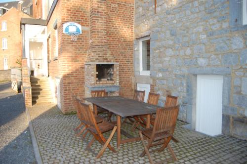 une table et des chaises ainsi qu'un bâtiment en briques avec une cheminée dans l'établissement Gîte de la Fontaine, à Beauraing