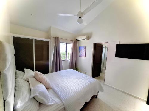 a bedroom with a bed with white sheets and pillows at Bright & Modern Apartment in Puerto Plata, Secure, and Central! in San Felipe de Puerto Plata