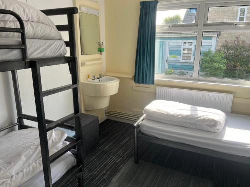 a bedroom with bunk beds and a sink and a window at Lulworth Hostel in West Lulworth