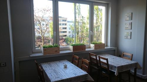 グディニャにあるHELLO Gdynia Hostelのダイニングルーム(テーブル2台、窓2つ付)