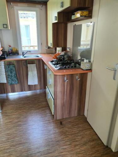 une cuisine avec des armoires en bois et un four à plaques de cuisson dans l'établissement Mobile home, à Agde