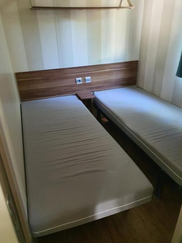 - 2 lits dans une petite chambre avec des murs en bois dans l'établissement Mobile home, à Agde