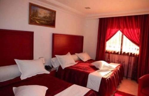 a bedroom with two beds with red and white sheets at Hotel El Dey 1 in Husseïn Dey