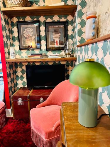 un salon avec une cheminée et une lampe verte dans l'établissement La Grange - Les Maisons des Pommiers, à Monceaux-en-Bessin