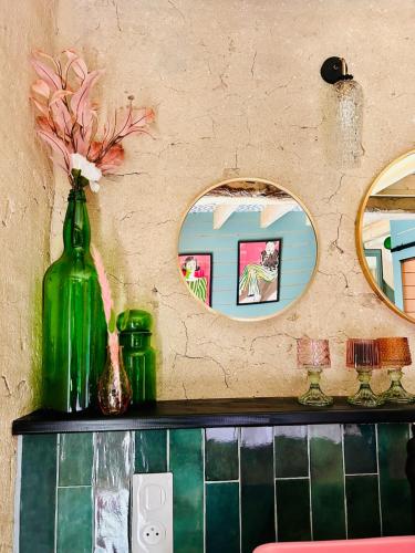 une bouteille verte posée sur un comptoir avec deux miroirs dans l'établissement La Grange - Les Maisons des Pommiers, à Monceaux-en-Bessin