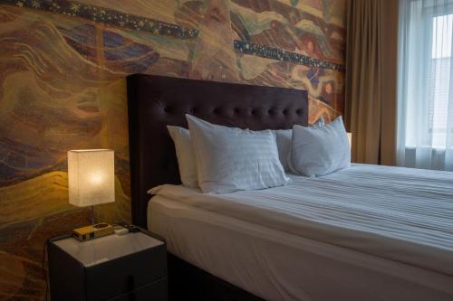 a bedroom with a bed with a painting on the wall at Agneta Apartamentai in Druskininkai