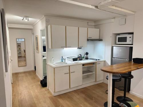 une cuisine avec des armoires blanches et une table en bois dans l'établissement Appartement tout équipé à coté de la Timone Marseille, à Marseille