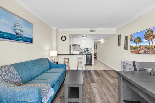a living room with a blue couch and a kitchen at Spectacular Oceanview Condos in Myrtle Beach