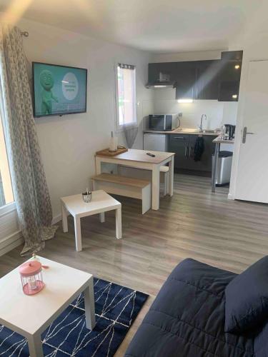 Il comprend un salon avec un canapé et des tables ainsi qu'une cuisine. dans l'établissement Studio proche mer avec jardin, à Ouistreham
