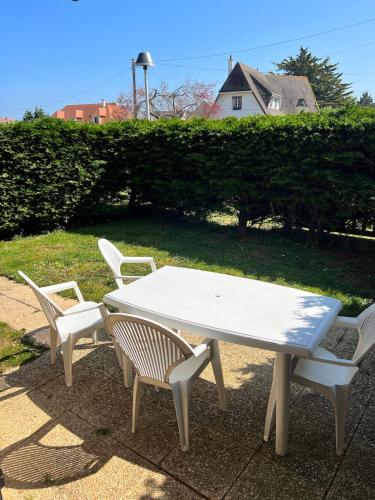 une table et deux chaises ainsi qu'une table et des chaises blanches dans l'établissement Studio proche mer avec jardin, à Ouistreham
