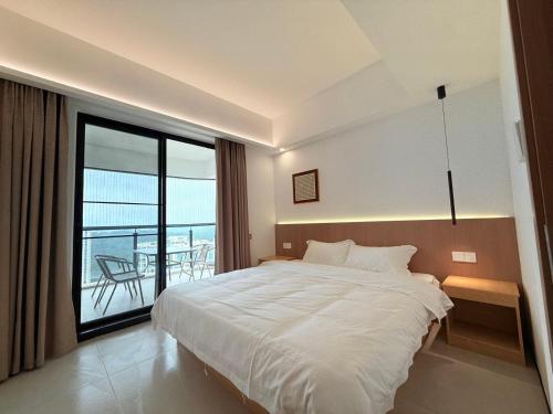 a bedroom with a large white bed and a balcony at Harbour Holiday -山海居 in Shantou