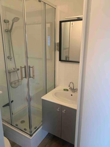 une salle de bain avec une douche en verre et un lavabo dans l'établissement Studio proche mer avec jardin, à Ouistreham
