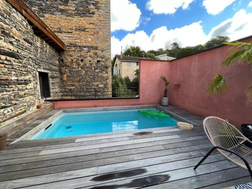 - une piscine sur une terrasse en bois avec un bâtiment dans l'établissement La terrasse des épices, à Caluire-et-Cuire
