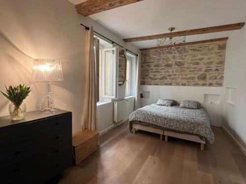 une chambre avec un lit et un mur en pierre dans l'établissement La terrasse des épices, à Caluire-et-Cuire