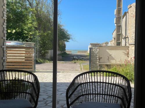 - deux chaises assises sur une terrasse couverte donnant sur l'océan dans l'établissement Horizon Bois by Melrose, à Asnelles