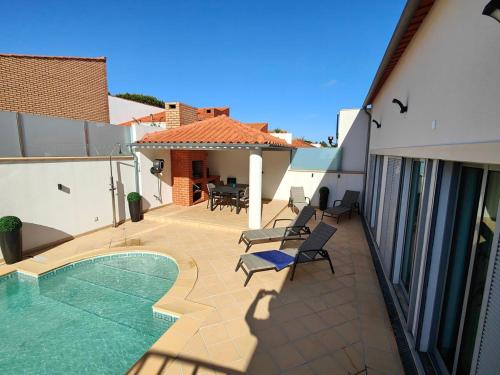 a patio with a swimming pool and chairs and a house at Villa Atlantica Torreira Piscine Salle de Jeux in Torreira