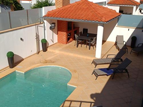 a patio with a pool and a table and chairs at Villa Atlantica Torreira Piscine Salle de Jeux in Torreira