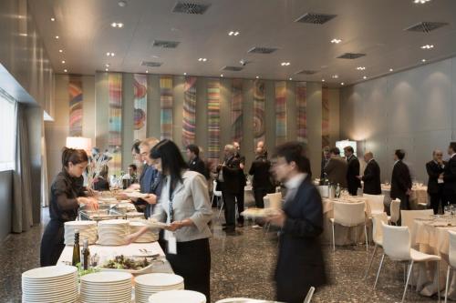 a group of people standing around a table with plates at UNA HOTELS T Hotel Cagliari in Cagliari