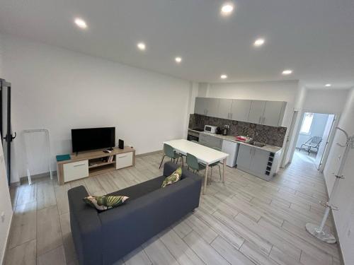 Una sala de estar con un sofá y una mesa y una cocina. en Casa Jonhy, en Faro