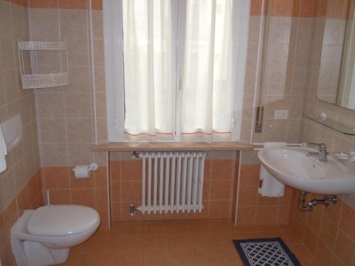 a bathroom with a toilet and a sink and a window at Albergo Elvira in Tabiano