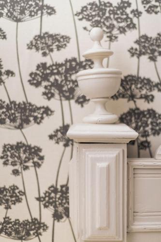 un vase blanc devant un mur avec du papier peint dans l'établissement Gîte du Rouard, à Camiers