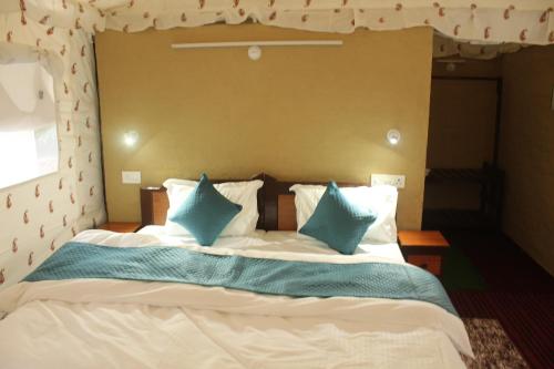 a bedroom with a large bed with blue pillows at Billing View Camp and Mud Houses,Bir in Aiju