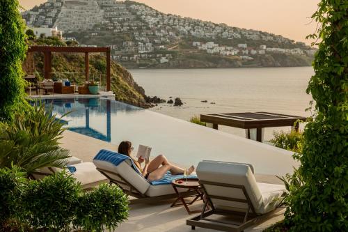 a woman sitting on a beach chair with a laptop at Allium Bodrum Resort & Spa in Yalıkavak