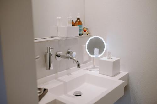 a white bathroom with a sink and a mirror at Mesnerhaus & Gourmetrestaurant Mesnerhaus mit 4 Hauben in Mauterndorf