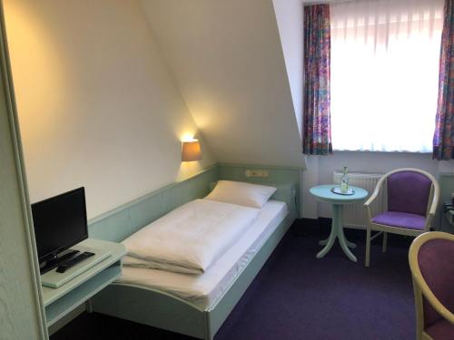 a small room with a bed and a desk with a computer at Hotel Weisses Lamm in Allersberg