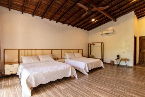 two beds in a room with wooden floors at Portales del Tayrona Garden Hotel in Calabazo