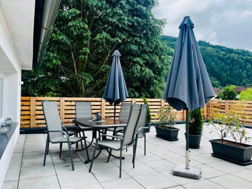 a patio with a table and chairs and umbrellas at Ferienwohnung Auszeit Döbriach in Döbriach
