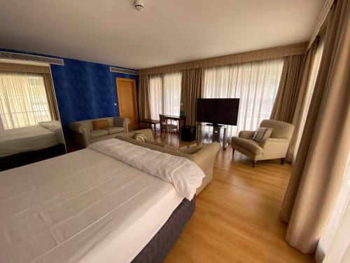 a bedroom with a bed and chairs and a television at U Hotel Villa-Gomá in Zaragoza