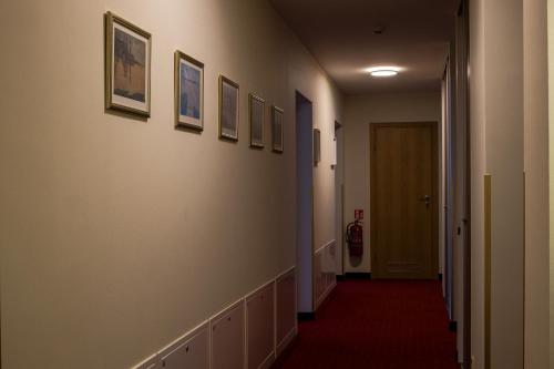 a hallway with pictures on the walls and a red carpet at Agneta Apartamentai in Druskininkai