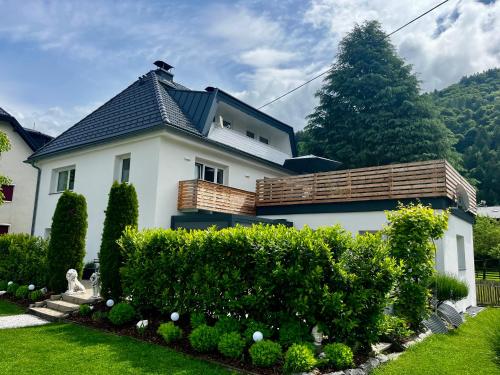 a white house with a fence and some bushes at Ferienwohnung Auszeit Döbriach in Döbriach