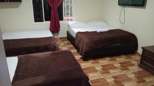 a room with two beds and a dresser and a window at Hotel Campestre Villa Alicia in Estación El Salto