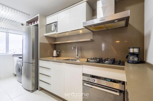 a kitchen with white cabinets and a stainless steel refrigerator at Lindo Apartamento em Itajaí CTP1103 in Itajaí
