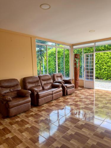 a living room with brown leather furniture and large windows at Hotel Campestre Villa Alicia in Estación El Salto