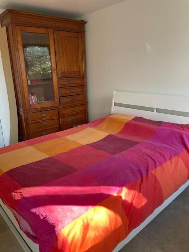 une chambre avec un lit coloré avec une commode dans l'établissement Petit gîte cosy proche de la mer, jardin privatif, à Clohars-Fouesnant