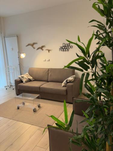 a living room with a couch and a potted plant at Cozy studio 700m from the Milan red metro in Sesto San Giovanni