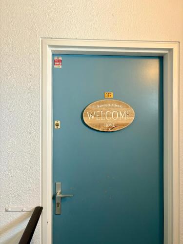 une porte bleue avec un panneau de bienvenue. dans l'établissement Appartement superbe vue -Climatisation - piscine - parking - 5MC317, au Barcarès