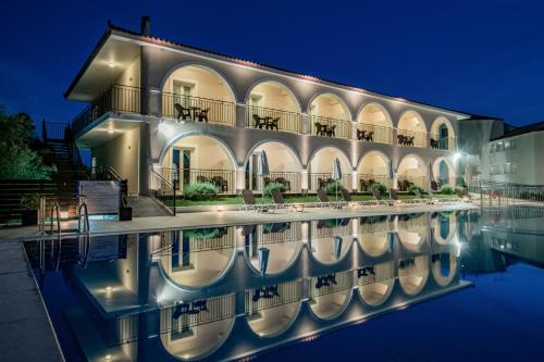 a building with a swimming pool at night at Hotel Varres in Zakynthos Town