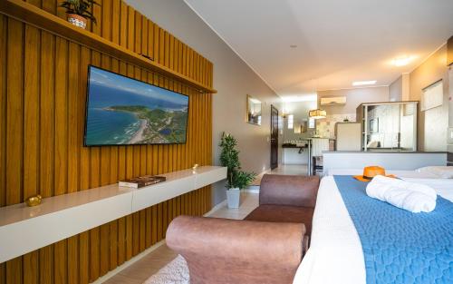 a bedroom with a bed and a tv on a wall at Pousada Natribus Rosa in Praia do Rosa