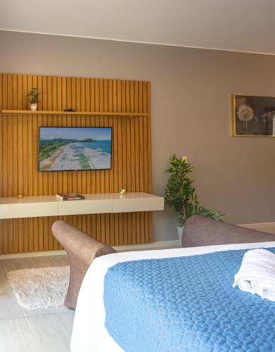 a bedroom with a bed and a tv on a wall at Pousada Natribus Rosa in Praia do Rosa