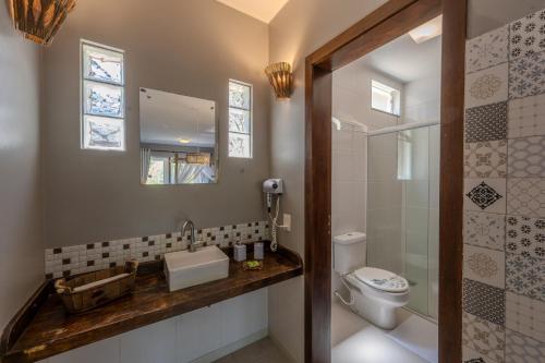 a bathroom with a toilet and a sink and a mirror at Pousada Natribus Rosa in Praia do Rosa