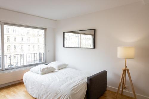une chambre blanche avec un lit et une fenêtre dans l'établissement Charming Moulin Rouge Studio, à Paris
