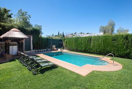 a swimming pool in a yard with chairs and a gazebo at Villa For Families los Agaves in La Cala de Mijas
