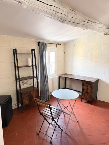 Cette chambre comprend un bureau, une table et une chaise. dans l'établissement Les chambres Saint-Roch, à Arles