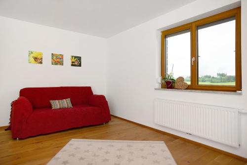 a red couch in a white room with a window at Ferienwohnung Auf Dem Haldershof in Wangen im Allgäu